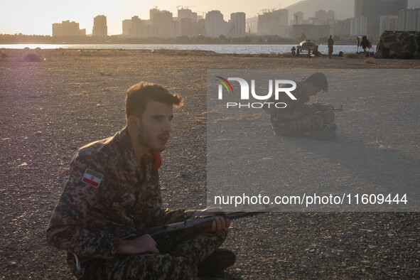 Two members of the Islamic Revolutionary Guard Corps (IRGC) hold AK-45 rifles while preparing to take part in a war game, which is a reconst...