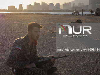 Two members of the Islamic Revolutionary Guard Corps (IRGC) hold AK-45 rifles while preparing to take part in a war game, which is a reconst...