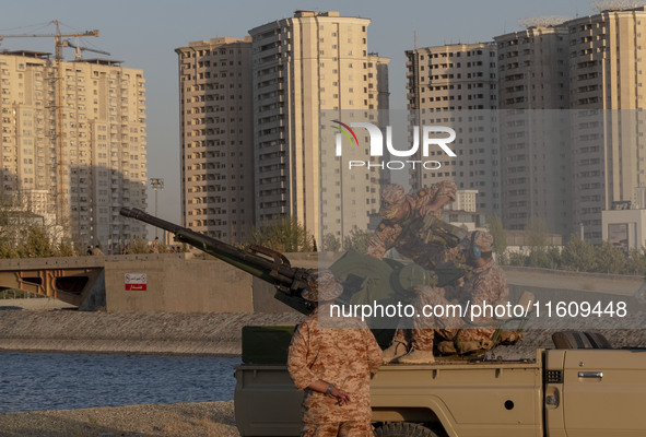 Islamic Revolutionary Guard Corps (IRGC) military personnel check an anti-aircraft gun in an area near housing complexes during the reconstr...