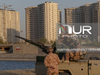 Islamic Revolutionary Guard Corps (IRGC) military personnel check an anti-aircraft gun in an area near housing complexes during the reconstr...