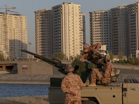 Islamic Revolutionary Guard Corps (IRGC) military personnel check an anti-aircraft gun in an area near housing complexes during the reconstr...