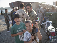 An Iranian schoolboy holds an AK-45 rifle while Islamic Revolutionary Guard Corps (IRGC) military personnel prepare to take part in a war ga...