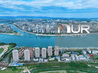 An aerial view shows high-rise buildings lining the riverside city, half landscape and half city, in Yichang, Hubei, China, on September 21,...