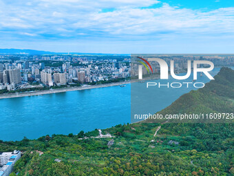 An aerial view shows high-rise buildings lining the riverside city, half landscape and half city, in Yichang, Hubei, China, on September 21,...