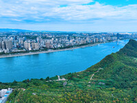 An aerial view shows high-rise buildings lining the riverside city, half landscape and half city, in Yichang, Hubei, China, on September 21,...