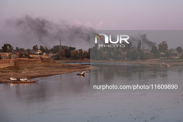 Smoke rises over the river Jhelum from burning waste material in Sopore, Jammu and Kashmir, India, on September 25, 2024. 