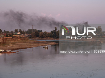 Smoke rises over the river Jhelum from burning waste material in Sopore, Jammu and Kashmir, India, on September 25, 2024. (