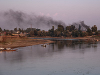 Smoke rises over the river Jhelum from burning waste material in Sopore, Jammu and Kashmir, India, on September 25, 2024. (