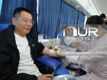 Primary school teachers donate blood on a mobile blood collection vehicle in Yancheng, China, on September 26, 2024. (