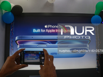 A man takes a picture of Apple's latest iPhone 16 billboard at Master Arts Shop in Srinagar, Jammu and Kashmir, on September 26, 2024. Accor...