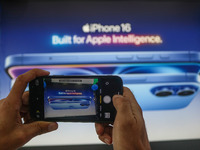 A man takes a picture of Apple's latest iPhone 16 billboard at Master Arts Shop in Srinagar, Jammu and Kashmir, on September 26, 2024. Accor...