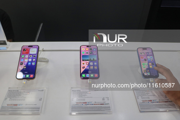 A customer checks Apple's latest iPhone 16 (right) series displayed for sale at Master Arts Shop in Srinagar, Jammu and Kashmir, on Septembe...