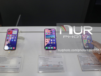 A customer checks Apple's latest iPhone 16 (right) series displayed for sale at Master Arts Shop in Srinagar, Jammu and Kashmir, on Septembe...