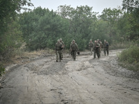 Servicemen of the 65th Separate Mechanized Brigade of the Armed Forces of Ukraine march along a dusty road during combat coordination in Ukr...