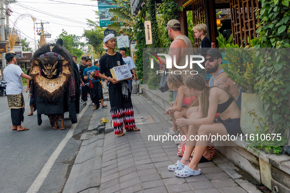 A group of children is seen performing Ngelawang, a traditional ritual featuring the Barong Bangkung, a barong with the head of a wild boar,...