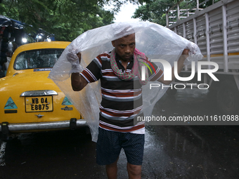 A laborer covers themselves with plastic sheets to protect from the monsoon rain in Kolkata, India, on September 26, 2024. (