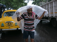 A laborer covers themselves with plastic sheets to protect from the monsoon rain in Kolkata, India, on September 26, 2024. (