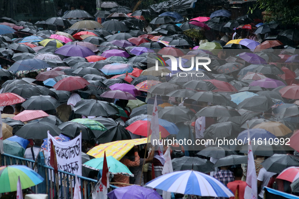 Citizens hold umbrellas and attend a protest rally against the rape and murder of a PGT woman doctor at the government-run R G Kar Medical C...