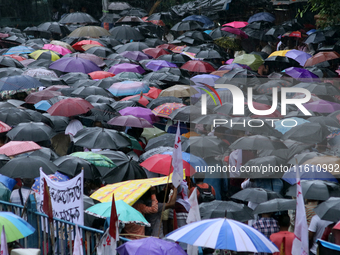 Citizens hold umbrellas and attend a protest rally against the rape and murder of a PGT woman doctor at the government-run R G Kar Medical C...