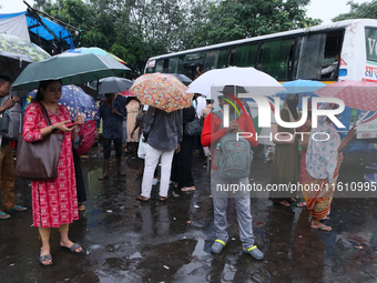 People hold umbrellas and wait for transportation in the monsoon rain in Kolkata, India, on September 26, 2024. (