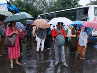 People hold umbrellas and wait for transportation in the monsoon rain in Kolkata, India, on September 26, 2024. (