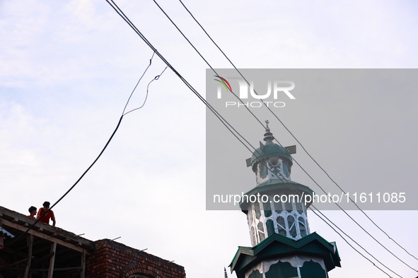 People sit as illegal power hooks are put on an electricity wire in Baramulla, Jammu and Kashmir, India, on September 27, 2024. 