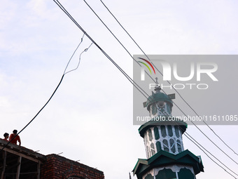 People sit as illegal power hooks are put on an electricity wire in Baramulla, Jammu and Kashmir, India, on September 27, 2024. (