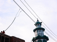 People sit as illegal power hooks are put on an electricity wire in Baramulla, Jammu and Kashmir, India, on September 27, 2024. (