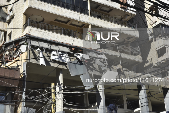 People and rescuers gather at the site of an Israeli airstrike that targets an apartment on al-Qaem Street in Beirut's southern suburbs on S...