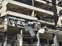 People and rescuers gather at the site of an Israeli airstrike that targets an apartment on al-Qaem Street in Beirut's southern suburbs on S...