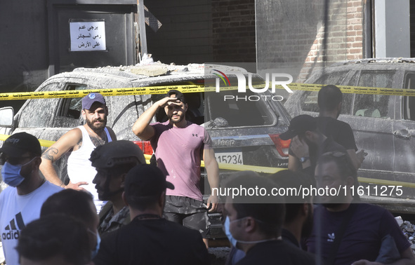 People and rescuers gather at the site of an Israeli airstrike that targets an apartment on al-Qaem Street in Beirut's southern suburbs on S...