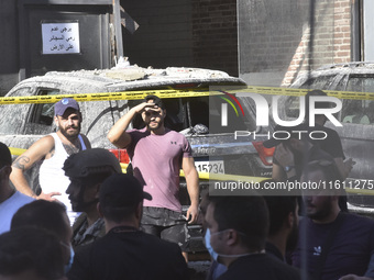 People and rescuers gather at the site of an Israeli airstrike that targets an apartment on al-Qaem Street in Beirut's southern suburbs on S...