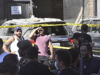 People and rescuers gather at the site of an Israeli airstrike that targets an apartment on al-Qaem Street in Beirut's southern suburbs on S...