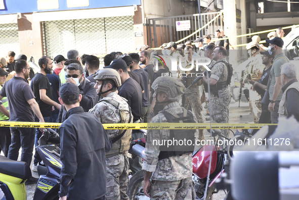 People and rescuers gather at the site of an Israeli airstrike that targets an apartment on al-Qaem Street in Beirut's southern suburbs on S...