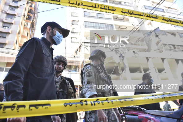 People and rescuers gather at the site of an Israeli airstrike that targets an apartment on al-Qaem Street in Beirut's southern suburbs on S...