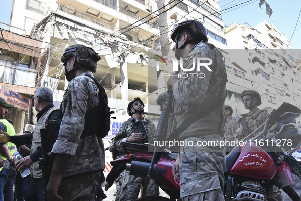 People and rescuers gather at the site of an Israeli airstrike that targets an apartment on al-Qaem Street in Beirut's southern suburbs on S...