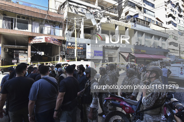 People and rescuers gather at the site of an Israeli airstrike that targets an apartment on al-Qaem Street in Beirut's southern suburbs on S...