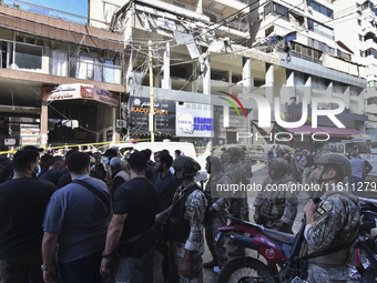 People and rescuers gather at the site of an Israeli airstrike that targets an apartment on al-Qaem Street in Beirut's southern suburbs on S...