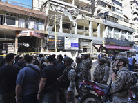 People and rescuers gather at the site of an Israeli airstrike that targets an apartment on al-Qaem Street in Beirut's southern suburbs on S...