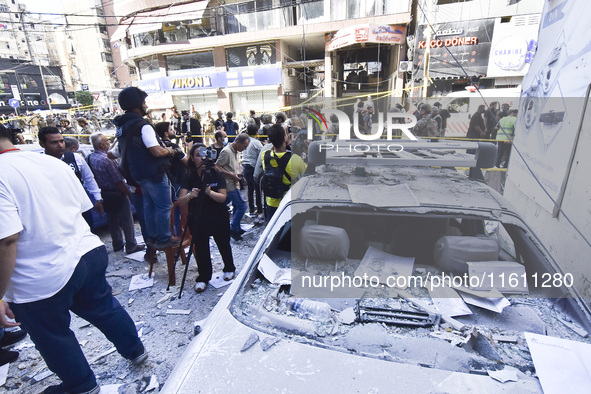 People and rescuers gather at the site of an Israeli airstrike that targets an apartment on al-Qaem Street in Beirut's southern suburbs on S...