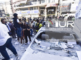 People and rescuers gather at the site of an Israeli airstrike that targets an apartment on al-Qaem Street in Beirut's southern suburbs on S...