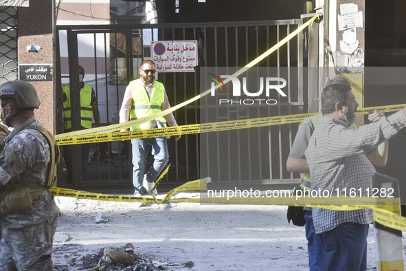 People and rescuers gather at the site of an Israeli airstrike that targets an apartment on al-Qaem Street in Beirut's southern suburbs on S...