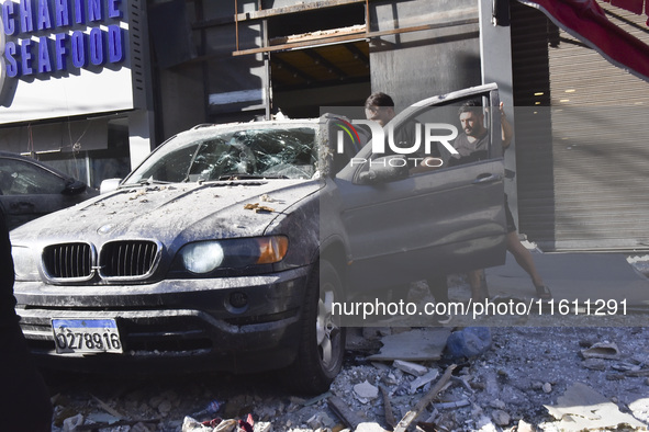 People and rescuers gather at the site of an Israeli airstrike that targets an apartment on al-Qaem Street in Beirut's southern suburbs on S...