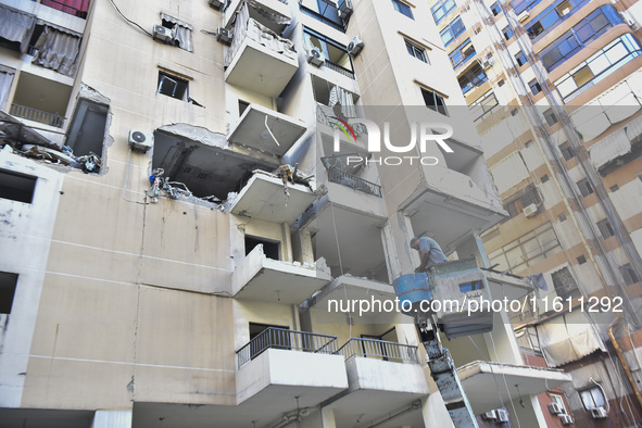 People and rescuers gather at the site of an Israeli airstrike that targets an apartment on al-Qaem Street in Beirut's southern suburbs on S...