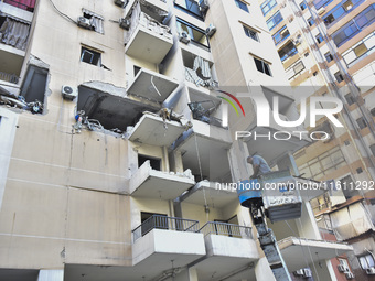 People and rescuers gather at the site of an Israeli airstrike that targets an apartment on al-Qaem Street in Beirut's southern suburbs on S...