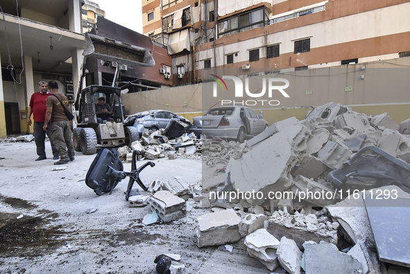 People and rescuers gather at the site of an Israeli airstrike that targets an apartment on al-Qaem Street in Beirut's southern suburbs on S...