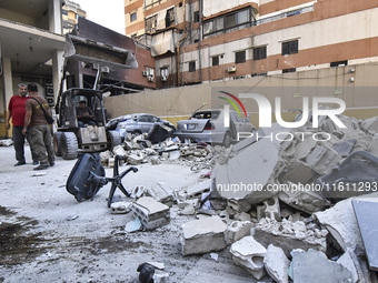 People and rescuers gather at the site of an Israeli airstrike that targets an apartment on al-Qaem Street in Beirut's southern suburbs on S...