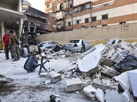 People and rescuers gather at the site of an Israeli airstrike that targets an apartment on al-Qaem Street in Beirut's southern suburbs on S...