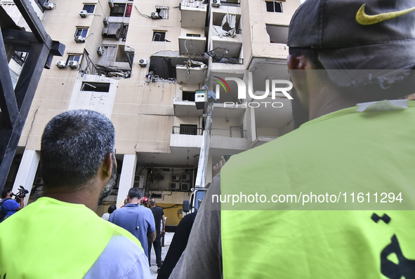 People and rescuers gather at the site of an Israeli airstrike that targets an apartment on al-Qaem Street in Beirut's southern suburbs on S...