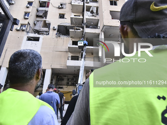 People and rescuers gather at the site of an Israeli airstrike that targets an apartment on al-Qaem Street in Beirut's southern suburbs on S...